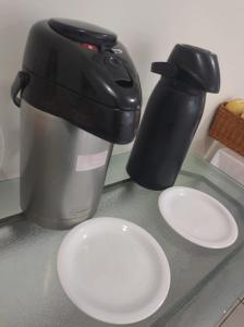 eine Kaffeemaschine und zwei weiße Teller auf der Theke in der Unterkunft RUBY HOSPEDAGENS in Indaiatuba