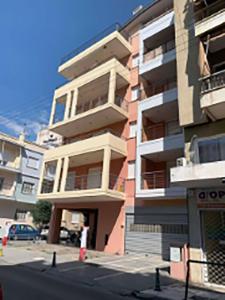 un edificio alto con un estacionamiento delante de él en Little Emerald - Central Spot Apartments en Volos