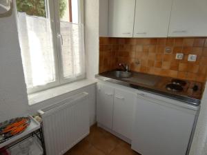 uma cozinha com armários brancos, um lavatório e uma janela em Appartement calme dans quartier résidentiel. em Nancy