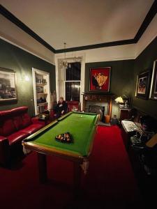 a man sitting in a living room with a pool table at Moorlands in Helensburgh