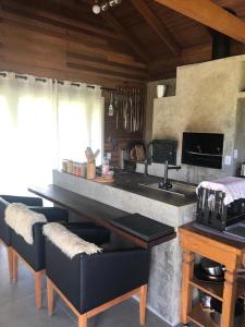 a kitchen with a counter with a sink and some chairs at Cabana Guimarães in Rancho Queimado