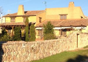 een groot geel huis met een stenen muur bij La Casa Rota Arahuetes in Arahuetes