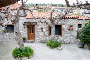 uma casa de pedra com duas árvores em frente em ''The Stone'' em Agios Vlasios