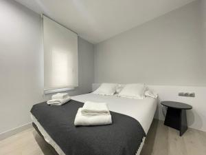 ein weißes Schlafzimmer mit einem Bett mit Handtüchern darauf in der Unterkunft Apartaments Voramar Roses in Roses