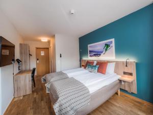 Nordfjord Hotell في نوردفيورديد: غرفة نوم بسرير كبير بجدار ازرق