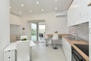 cocina con armarios blancos, mesa y sillas en Casa Vacanza LaLu LeLo, en Castellabate