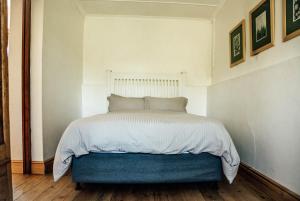 a bedroom with a bed with a blue ottoman at Bokrivier Cottages in Greyton