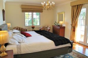 een slaapkamer met een groot wit bed en een kroonluchter bij Magnificent Funchal Villa Villa Luzia 5 Bedrooms Sea City Views Pool Table in Funchal