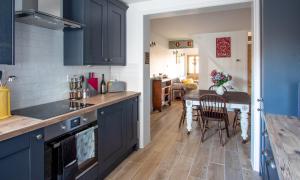 a kitchen with blue cabinets and a wooden table at Stylish Town Centre House with Garden and Parking Opposite in Bury Saint Edmunds