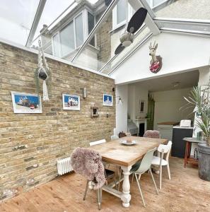 uma mesa e cadeiras num quarto com uma parede de tijolos em Home away from Home - Broadstairs beautiful family seaside house with garden and parking em Kent