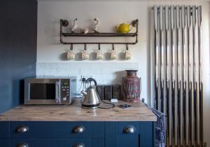 a kitchen with a counter with a microwave and a stove at Stylish Town Centre House with Garden and Parking Opposite in Bury Saint Edmunds +13 photos