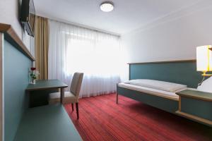 um quarto com uma cama, uma secretária e uma janela em Hotel Kehrenkamp em Hagen