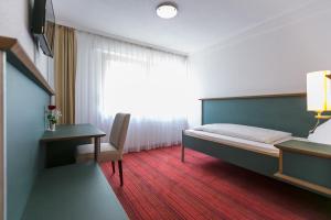a bedroom with a bed and a desk and a window at Hotel Kehrenkamp in Hagen