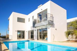 a white house with a swimming pool in front of it at Villa Azinhança do Mar in Lourinhã