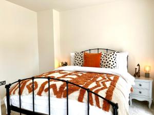 1 dormitorio con cama blanca y negra con almohadas de color naranja en New Stylish Cambridge Townhouse (Free parking), en Long Stanton