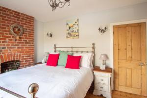 um quarto com uma cama com almofadas vermelhas e verdes em Stylish Town Centre House with Garden and Parking Opposite em Bury Saint Edmunds