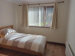 een slaapkamer met een bed en een raam bij Impeccable 5-Bed Cottage in fahan buncrana in Buncrana