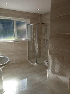 La salle de bains est pourvue d'une douche et d'un lavabo. dans l'établissement Impeccable 5-Bed Cottage in fahan buncrana, à Buncrana