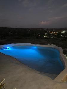 una piscina azul por la noche con una ciudad en Killa in 