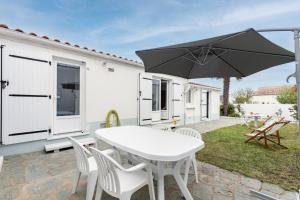 a patio with a white table and chairs and an umbrella at L'Argentine, Maison typique pour 5 a Saint Gilles-croix-de-vie in Saint-Gilles-Croix-de-Vie