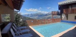 a swimming pool with chairs and mountains in the background at Goélia Les Chalets des Deux Domaines in Peisey-Nancroix