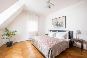 a white bedroom with a large bed with white pillows at St. George Apartments in Prague