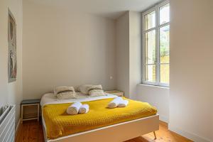 sypialnia z żółtym łóżkiem i ręcznikami w obiekcie Le Patio - Bel Appartement de caractère hypercentre de Vannes w mieście Vannes