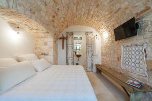um quarto com uma cama e uma televisão numa parede de tijolos em Trulli 18cinquantanove em Cisternino