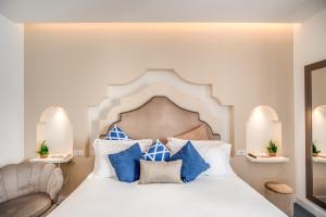 a bedroom with a large white bed with blue pillows at Hotel Sorrento City in Sorrento