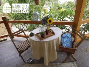 a table with a sunflower and glasses on a patio at Málnafröccs Vendégház Nagymaros in Nagymaros