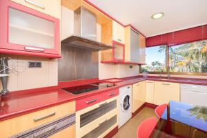 a kitchen with red cabinets and a stove top oven at Apto Villajoyosa 1ª línea in Villajoyosa