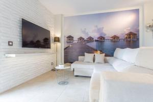 sala de estar con sofá blanco y TV de pantalla plana en Piso de 2 habitaciones, 3 piscinas y cerca del mar en Rosas