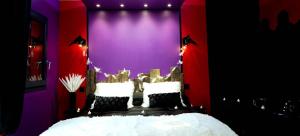 a bedroom with a bed with purple and purple walls at La Magie d'une Nuit in Agde