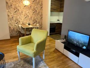 ein Wohnzimmer mit einem grünen Stuhl und einem TV in der Unterkunft CITY in Banja Luka