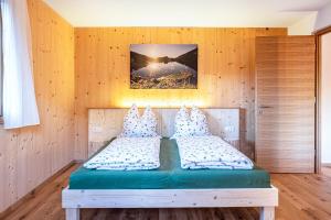 ein Schlafzimmer mit einem Bett in einer Holzwand in der Unterkunft Mittnackerhof Apartment Kamille in Sarntal