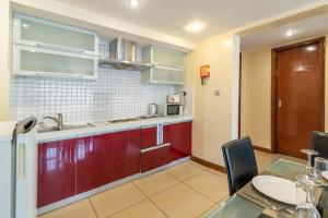 een keuken met rode kasten, een wastafel en een tafel bij Lenana Suites in Nairobi