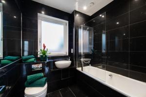 een badkamer met een toilet, een wastafel en een bad bij London Nino Apartments in Londen