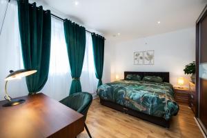 um quarto com uma cama, uma secretária e cortinas verdes em London Nino Apartments em Londres
