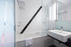 ein weißes Bad mit einem Waschbecken und einer Dusche in der Unterkunft Holiday Inn Bern Westside, an IHG Hotel in Bern