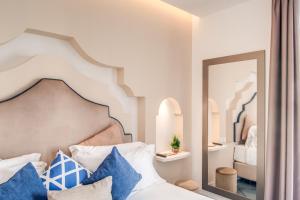 a bedroom with a bed with blue pillows and a mirror at Hotel Sorrento City in Sorrento