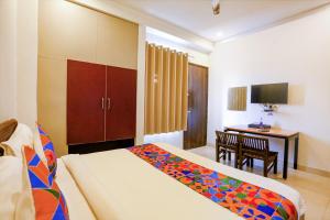 a hotel room with a bed and a desk and a table at FabHotel Novel Suites in New Delhi