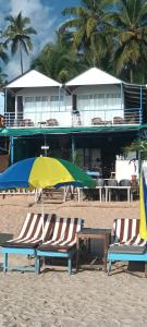 Royal Castle Resort palolem, canacona في محطة كاناكونا: كرسيين للشاطئ ومظلة على الشاطئ