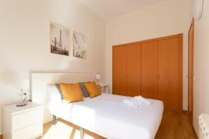 AB North Barcelona Apartments في برشلونة: غرفة نوم بسرير أبيض وخزانة خشبية
