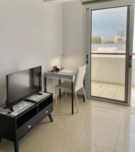 Cyprus Penelope في لارنكا: غرفة معيشة مع مكتب وتلفزيون وطاولة