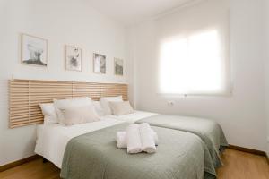 AB North Barcelona Apartments في برشلونة: غرفة نوم بسريرين وملاءات بيضاء ونافذة