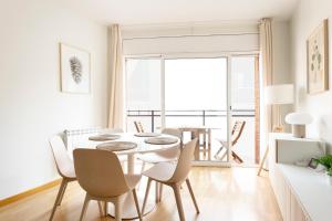 AB North Barcelona Apartments في برشلونة: غرفة طعام بيضاء مع طاولة وكراسي