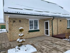 una casa de ladrillo con nieve encima en Apartamentai Baltas gandras en Naisiai