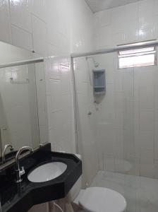 Baño blanco con lavabo y aseo en Recanto das Palmeiras Alter do Chão, en Alter do Chao