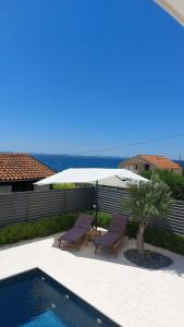 einen Pool mit 2 Liegestühlen und einem Sonnenschirm in der Unterkunft Apartments Kovacev in Zadar