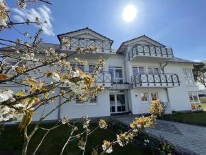 een groot wit huis met de zon in de lucht bij Villa Judith App. 3 Silbermöwe in Binz